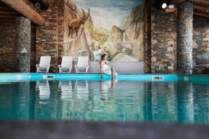 a woman sitting in the water in a swimming pool at Residence Les Hauts Bois - maeva Home in Aime-La Plagne