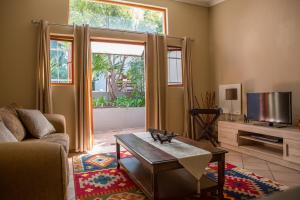 uma sala de estar com um sofá, uma mesa e uma televisão em Moonflower Cottages em Joanesburgo