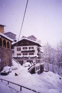 un edificio coperto di neve con auto parcheggiate all'interno di Albergo - B&B Alpina a Premadio