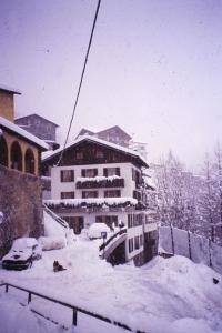 a building covered in snow with cars parked in it at Albergo - B&B Alpina in Valdidentro