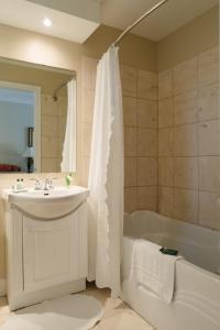 Green Acres Inn في كينغستون: حمام مع حوض وحوض استحمام ومرحاض