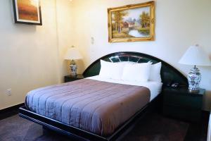 a hotel room with a bed and two lamps and a picture at Paris Suites Hotel in Queens