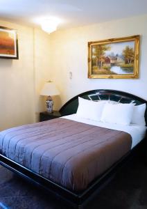 a bedroom with a large bed with a painting on the wall at Paris Suites Hotel in Queens