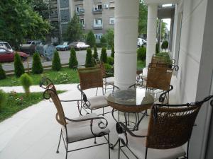 - un groupe de chaises et une table sur une terrasse couverte dans l'établissement Vila Apolo, à Belgrade