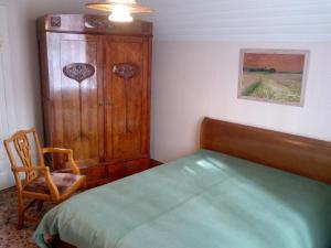 1 dormitorio con 1 cama, armario de madera y silla en Villa Florio, en Jūrmala