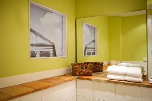 baño con paredes verdes y encimera con toallas en Pension La Casa dei Colori, en Weimar