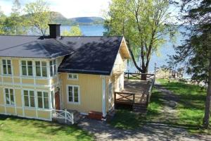 ein gelbes Haus mit Blick auf das Wasser in der Unterkunft Salsåker Herrgård in Salsåker