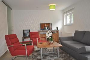 a living room with a couch and red chairs at Hotel Zum Stern in Rauischholzhausen
