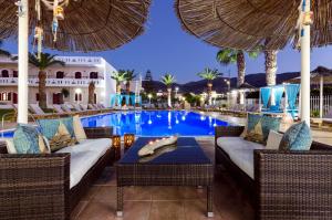 a resort with a swimming pool with chairs and a table at Stelios Gardens in Malia