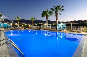 a large pool with palm trees and blue water at Stelios Gardens in Malia