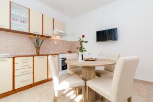 a kitchen with a wooden table and white chairs at Apartment Red Rose in Kaštela