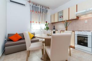 a kitchen and dining room with a table and a couch at Apartment Red Rose in Kaštela