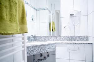 a white bathroom with a sink and a mirror at Hotel Wagner Am Marktplatz in Bad Wimpfen