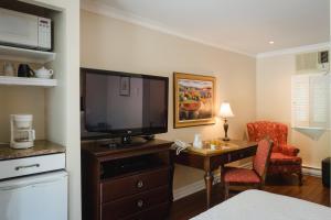 um quarto de hotel com uma televisão e uma secretária com uma cadeira em Green Acres Inn em Kingston