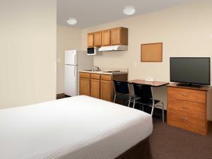 a hotel room with a bed and a desk with a television at WoodSpring Suites Kansas City Lenexa in Lenexa
