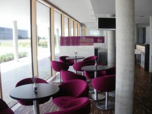 un restaurante con sillas moradas, mesas y ventanas en iQ-Hotel Ulm, en Ulm