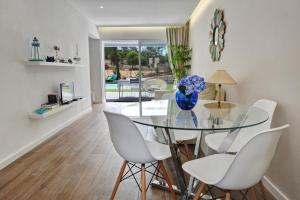 une salle à manger avec une table en verre et des chaises blanches dans l'établissement 3 Villas - Praia da Falesia, à Albufeira