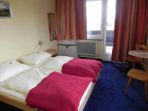 Habitación de hotel con cama con sábanas rojas y blancas en Hotel Berghof Tauplitzalm, en Tauplitzalm