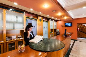a woman sitting at a desk talking on a cell phone at Hotel Del Val in Andújar