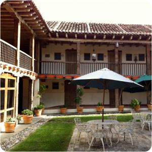 a table and chairs with an umbrella in front of a building at Hotel Santa Clara in San Cristóbal de Las Casas