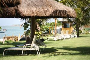 un groupe de chaises et un parasol sur l'herbe dans l'établissement Paraíso dos Corais, à Guarajuba