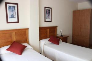 two beds in a room with red pillows on them at Hotel Oreneta in Altafulla