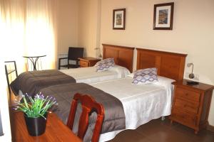 a bedroom with two beds and a table and a desk at Hotel Oreneta in Altafulla