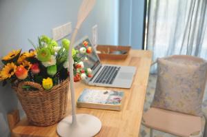 a wooden table with a laptop and a basket of flowers at Kiri Tawan in Ban Tai