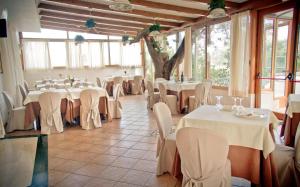 una stanza con tavoli e sedie bianchi e un albero di Park Hotel La Grave a Castellana Grotte