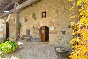 un edificio de piedra con puerta de madera y patio en Vivienda rural La Otra Casa, en Arenas de Iguña