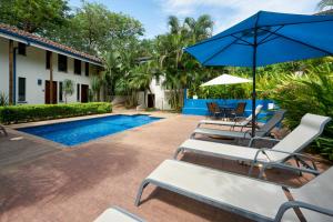 a group of chairs and umbrellas next to a swimming pool at Tamarindo Blue Apartments in Tamarindo