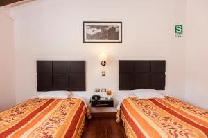 Hostal & Apartments El Triunfo في كوسكو: سريرين في غرفة فندق مع سريرين sidx sidx