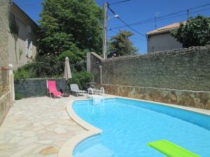 uma piscina num quintal com uma parede de pedra em La Maison des Vendangeurs à Puisserguier em Puisserguier