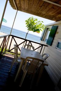 een tafel en stoelen op een veranda met uitzicht op de oceaan bij Camping La Focetta Sicula in SantʼAlessio Siculo