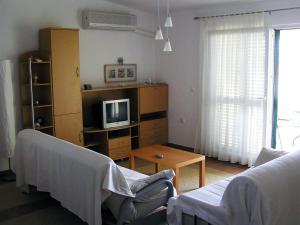 a living room with a couch and a tv at Maglić Apartment in Duće