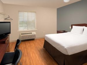 a bedroom with a bed and a desk and a television at WoodSpring Suites Kansas City Liberty in Liberty