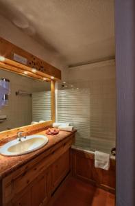 a bathroom with a sink and a mirror and a tub at Hotel Le Pelvoux in Les Menuires