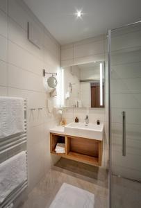 a white bathroom with a sink and a shower at Hotel Huberhof in Innsbruck