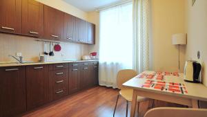 a kitchen with wooden cabinets and a table with chairs at Apartment Evia in Saint Petersburg