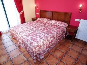 a bedroom with a bed and a pink wall at Apartamentos Villa de Cabrales in Arenas de Cabrales