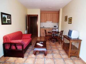 a living room with a red couch and a table at Apartamentos Villa de Cabrales in Arenas de Cabrales