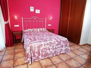 a pink bedroom with a bed and a red wall at Apartamentos Villa de Cabrales in Arenas de Cabrales