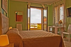 um quarto com uma cama e uma grande janela em Casa vacanze Sandalia em Bosa