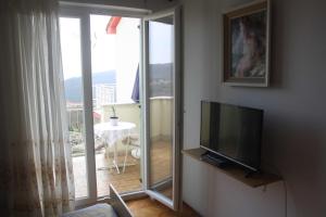 a living room with a flat screen tv and a balcony at Branka Apartments in Labin