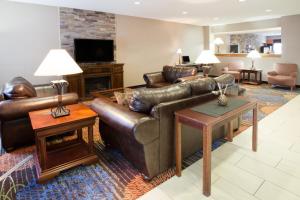a living room with a leather couch and tables at Baymont by Wyndham Auburn in Auburn