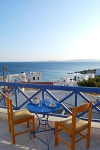 een tafel en stoelen op een balkon met uitzicht op de oceaan bij Athos Studios in Tinos Town