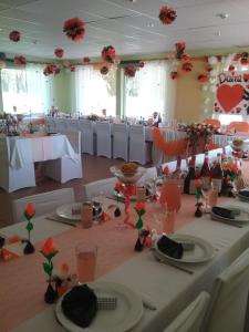 a banquet hall with white tables and red flowers at Atpūtas komplekss Lakši in Usma