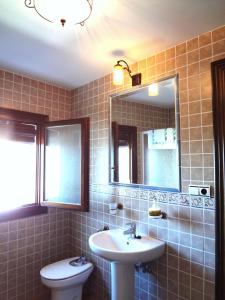 a bathroom with a sink and a toilet and a mirror at Hotel Rural Poqueira II in Capileira