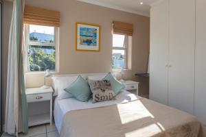 a bedroom with a bed and two windows at Plett's Life in Plettenberg Bay