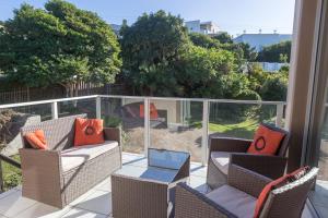 a patio with chairs and tables on a balcony at Plett's Life in Plettenberg Bay